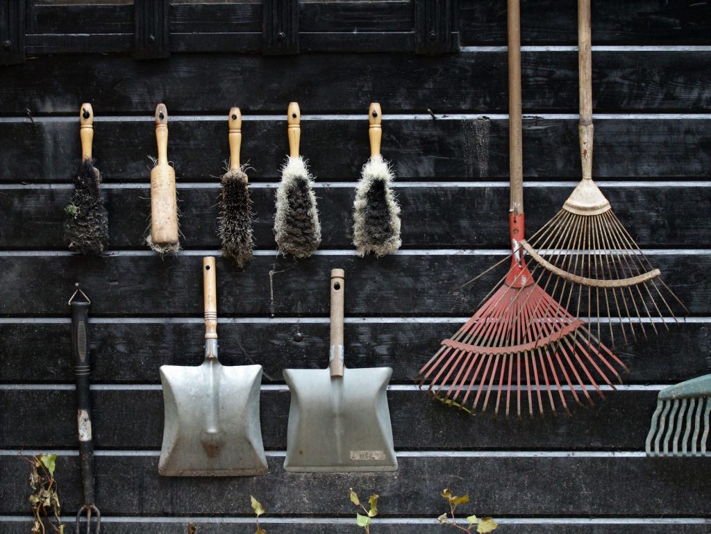 Garden tools neatly hanging on a dark wooden wall