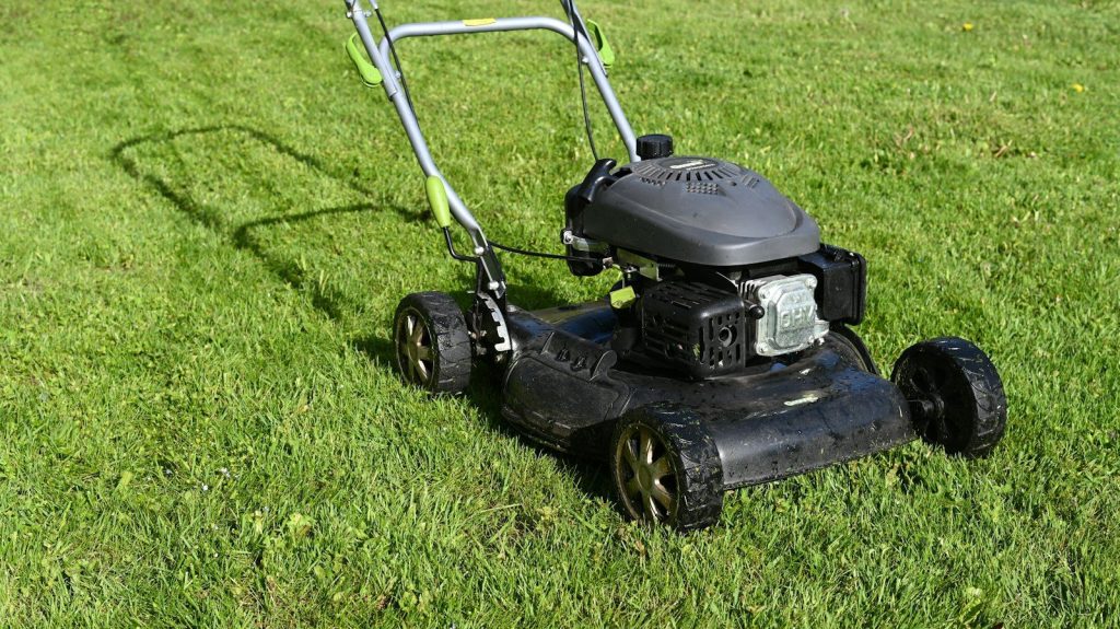 Push lawn mower standing on freshly cut grass
